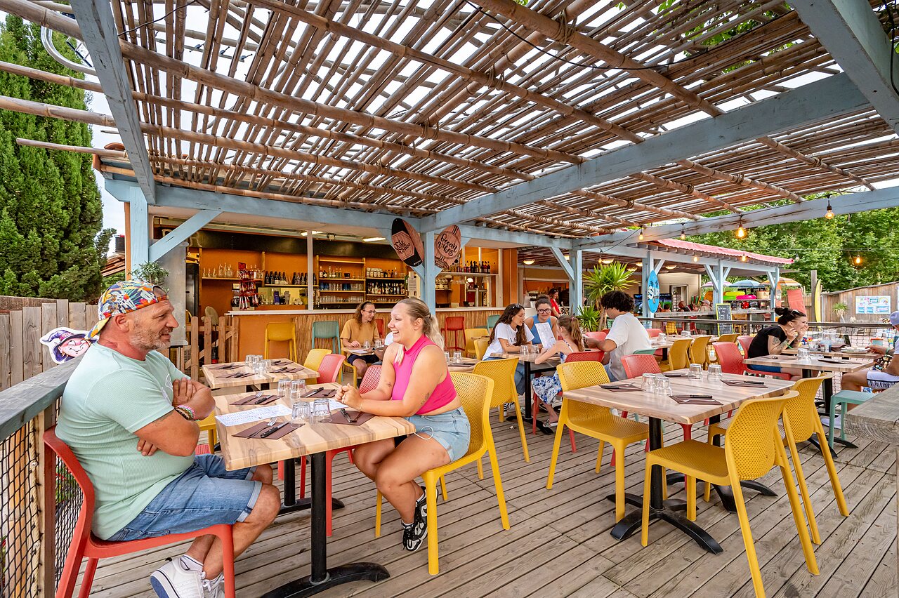 Terraza de restaurante animada con bar exterior en el camping CAPFUN El Moli en Elne (66).