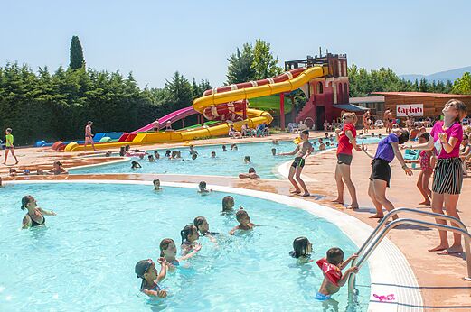 Piscina exterior con toboganes gigantes y niños en el camping CAPFUN El Moli en Elne (66).