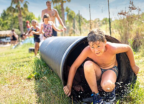 Ni�o saliendo de t�nel acu�tico, juego de agua en camping CAPFUN El Moli en Elne (66).