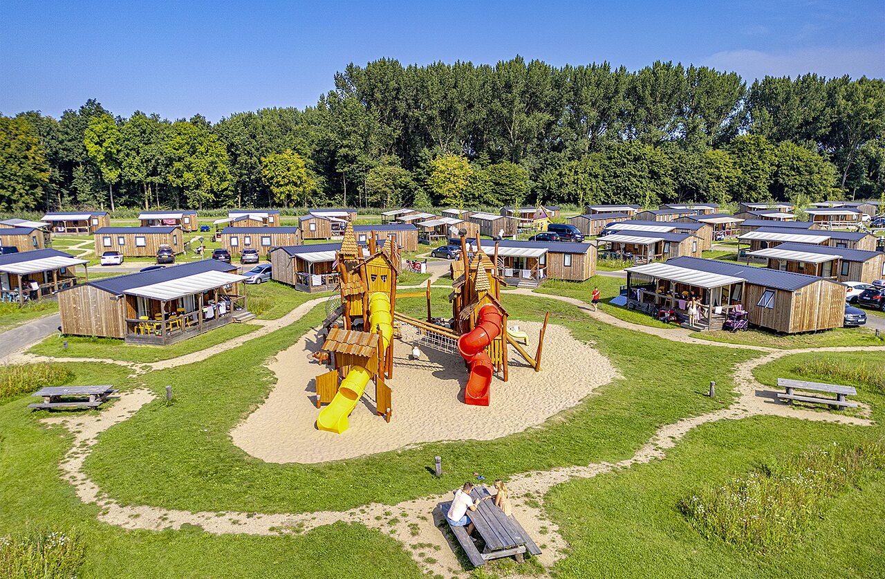 Parque infantil, casas m�viles y vegetaci�n en camping CAPFUN Erkemederstrand en Zeewolde.