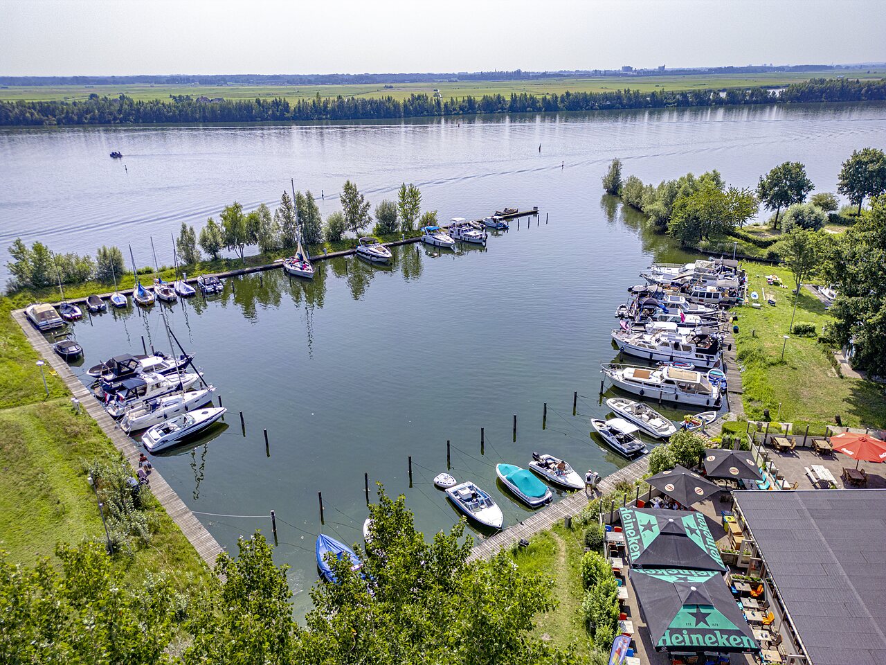 Marina con barcos amarrados y bar junto al lago en camping CAPFUN Erkemederstrand en Zeewolde.