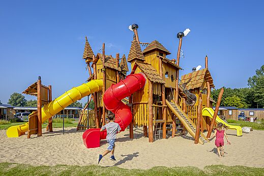 Parque infantil de madera con toboganes y niños en el camping CAPFUN Erkemederstrand en Zeewolde.