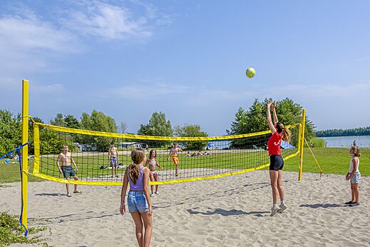 Partido de voleibol de playa en la playa con niños en el camping CAPFUN Erkemederstrand en Zeewolde.