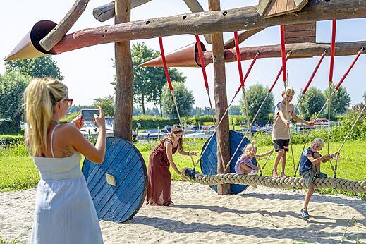 Zona de juegos de madera y cuerda con niños en el camping CAPFUN Erkemederstrand en Zeewolde.