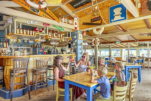 Bar y restaurante con clientes disfrutando de bebidas en el camping CAPFUN Erkemederstrand en Zeewolde.