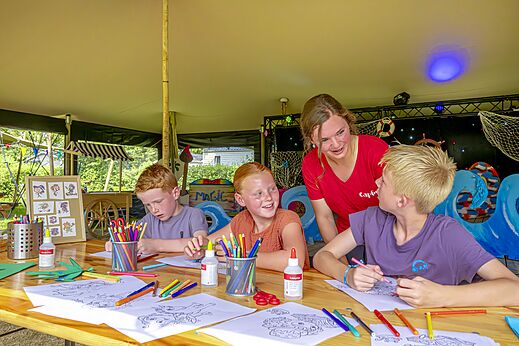 Niños participando en actividad de colorear con animador en camping CAPFUN Erkemederstrand en Zeewolde.
