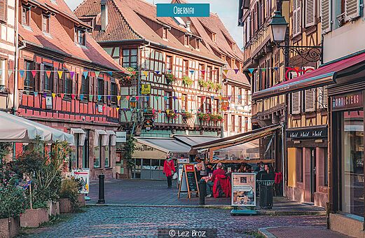 Calle adoquinada animada con casas de entramado de madera en Obernai, Alsacia.