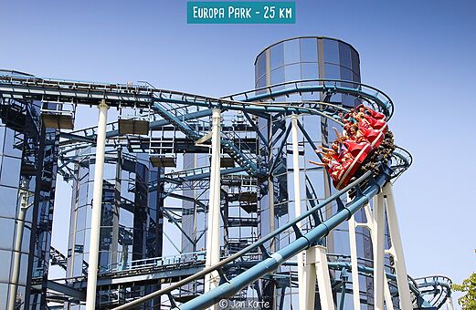 Montaña rusa azul con vagón rojo y pasajeros en Europa Park, parque de atracciones.