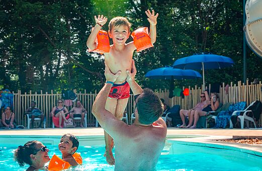 Familia sonriente jugando en la piscina del camping VAGUES OCEANES Lac d'Erstein (67).