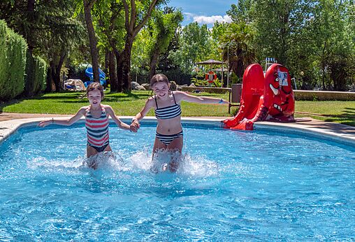 Dos ni�os juegan en la piscina con tobog�n en el camping CAPFUN El Escorial en El Escorial, Madrid.