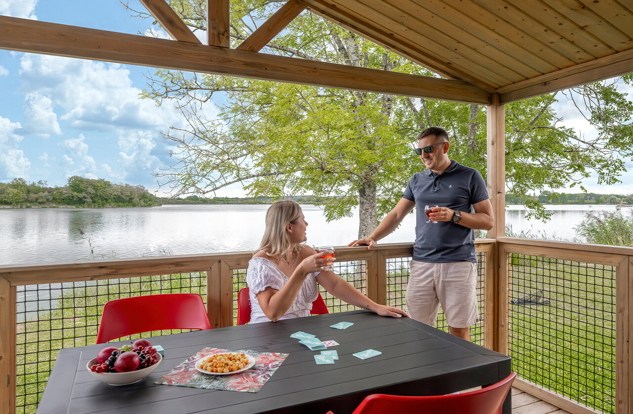 Terraza de alojamiento, pareja y vista al lago en el camping CLICOCHIC Etang de la Mutche en HARPRICH (57).