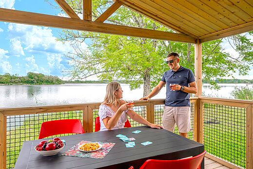 Pareja en terraza de alojamiento con vista al lago en el camping CLICOCHIC Etang de la Mutche en HARPRICH (57).