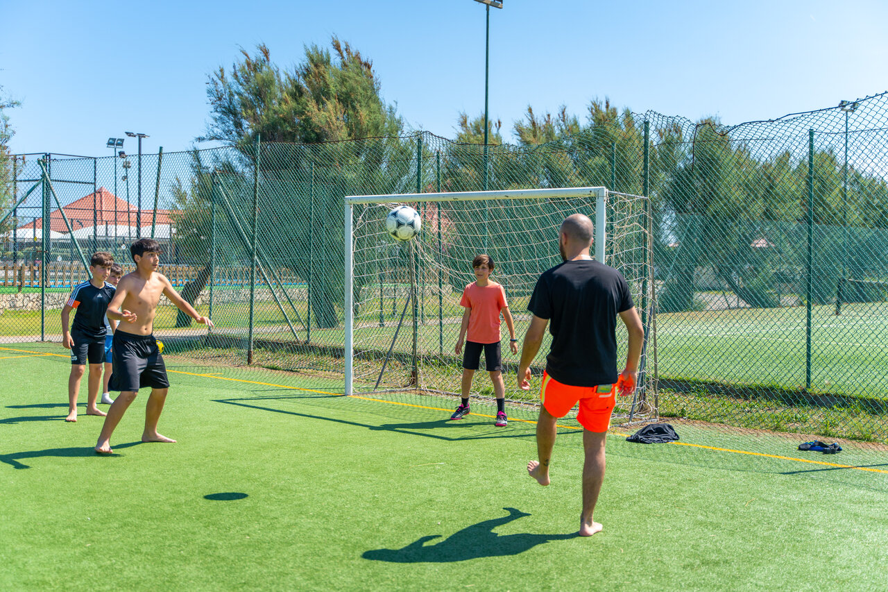 Hu�spedes jugando al f�tbol en campo sint�tico en camping CAPFUN Europing Tarquinia.
