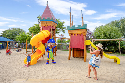 Zona de juegos con toboganes, estructuras de madera y arena en el camping CAPFUN L'Eve en Saint-Marc-sur-Mer (44).