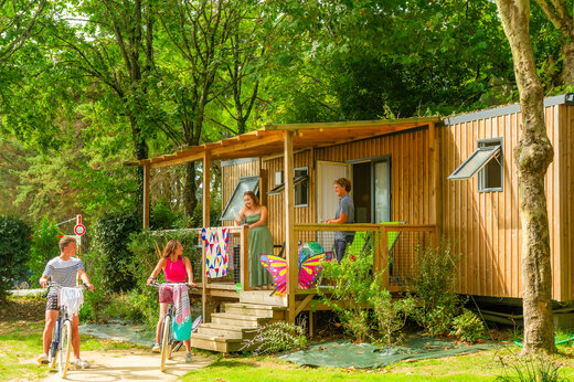 Casa móvil de madera, terraza, jóvenes en bicicleta en camping CAPFUN L'Eve (44).