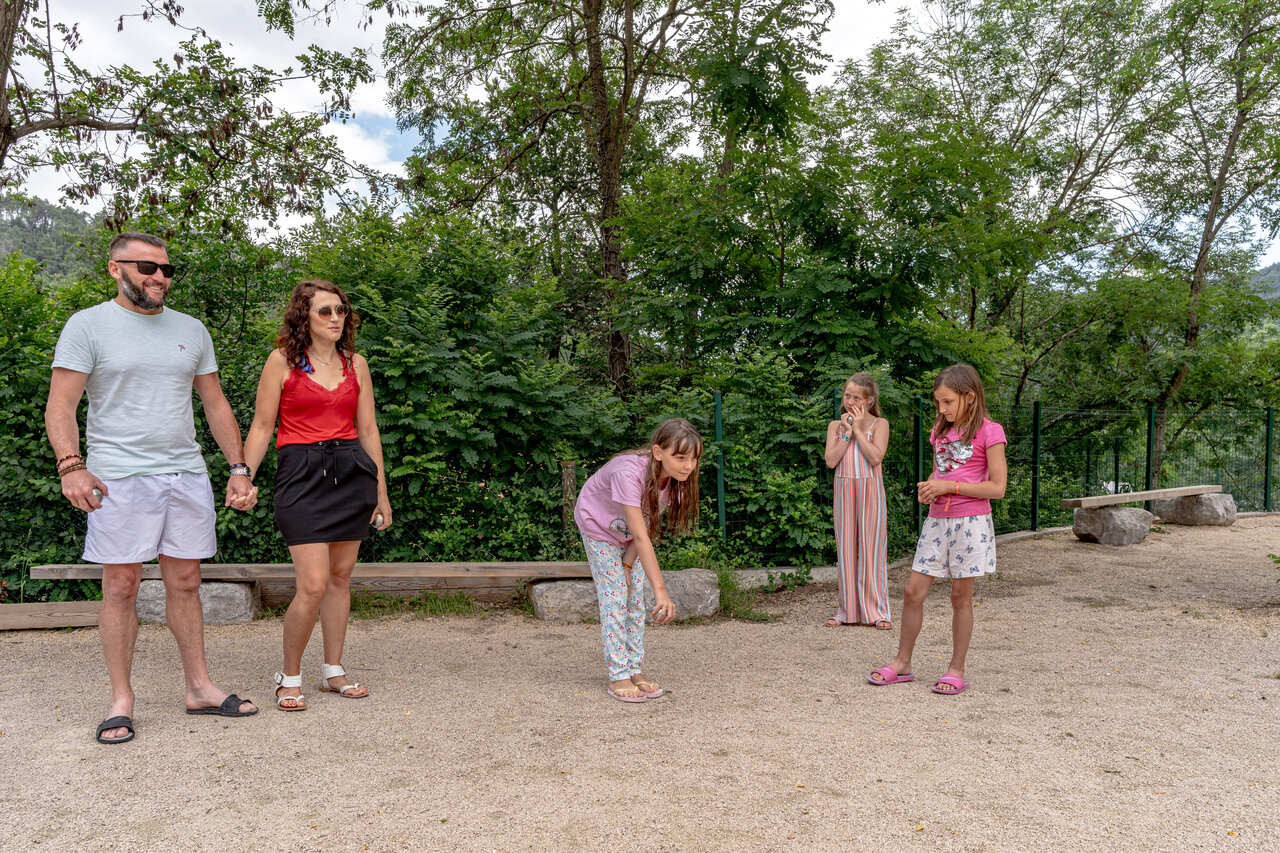 Familia jugando a la petanca en el campo de juegos del camping CLICOCHIC Eyrieux en Les OLLIERES-SUR-EYRIEUX.