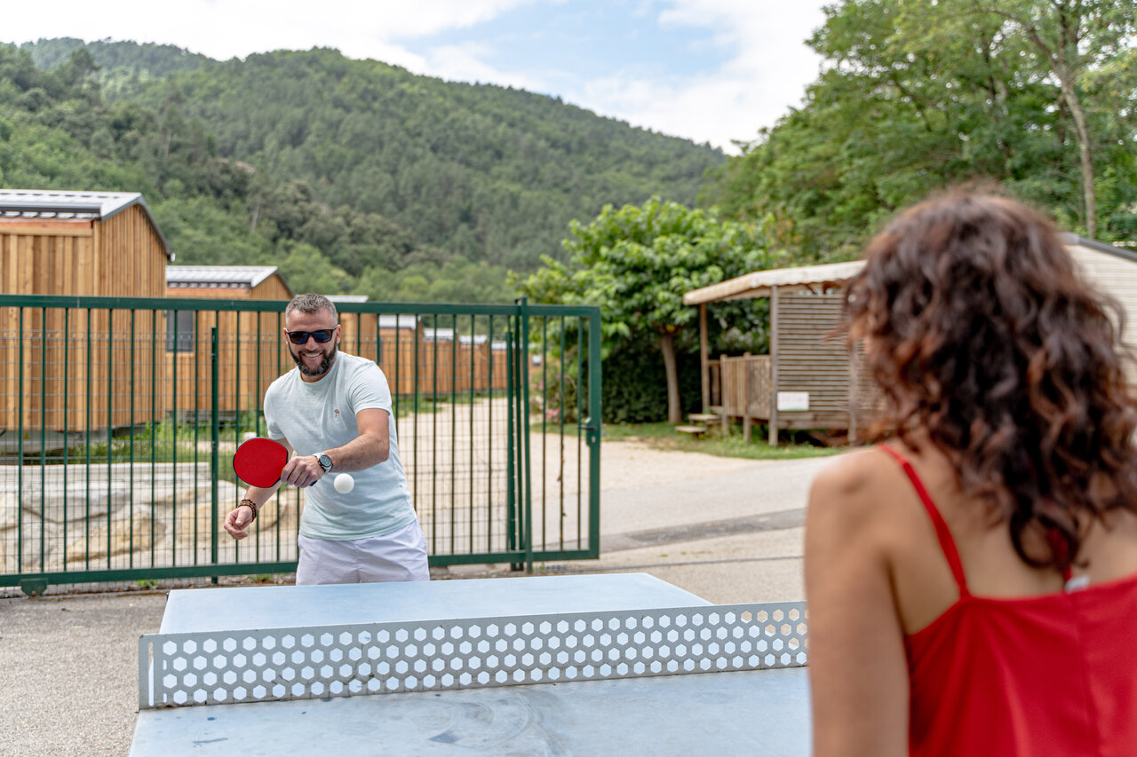 Pareja jugando al ping-pong cerca de alojamientos en el camping CLICOCHIC Eyrieux en Les OLLIERES-SUR-EYRIEUX.