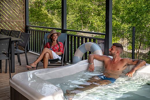 Pareja disfrutando de un jacuzzi privado en terraza en el camping CLICOCHIC Eyrieux.
