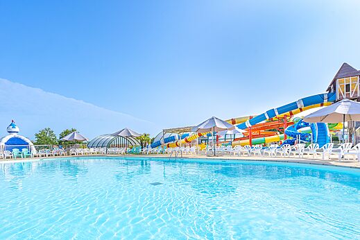 Piscina exterior, toboganes acuáticos y sillas en el camping CAPFUN Falaises en Gonneville sur Mer (14).