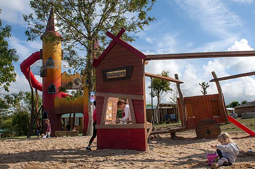 Zona de juegos con torre colorida, tobogán y casita en el camping CAPFUN Falaises en Gonneville sur Mer (14).