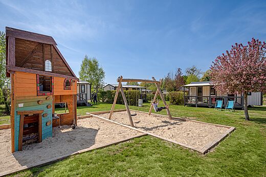Zona de juegos, columpio y cabaña en el camping CLICOCHIC Ferme des Aulnes en NAMPONT SAINT MARTIN (80).