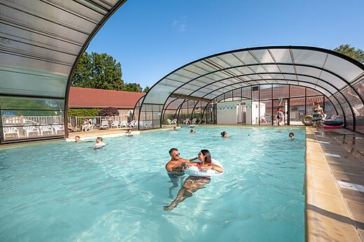 Piscina cubierta y descubierta con bañistas en el camping CLICOCHIC Ferme des Aulnes NAMPONT SAINT MARTIN.