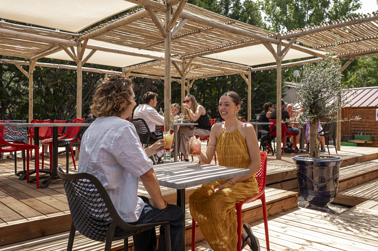 Terraza de bar y restaurante, clientes con c�cteles en el camping CLICOCHIC Filament en Thoiras.