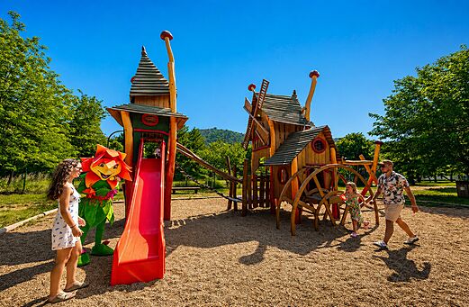 Parque infantil de madera con tobogán y mascota en el camping CLICOCHIC Filament en Thoiras (30).