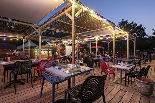 Terraza de restaurante y bar animada por la noche en camping CLICOCHIC Filament Thoiras.