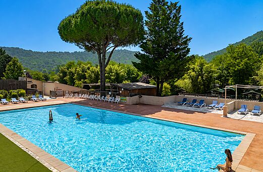 Piscina exterior con bañistas y sillas en el camping CLICOCHIC Filament en Thoiras (30).