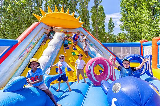 Niños divirtiéndose en un gran castillo hinchable con tobogán en el camping VAGUES OCEANES Au Flamenco en Argelès-sur-Mer (66).