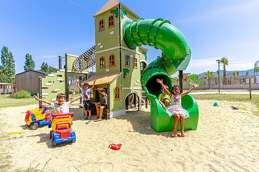 Zona de juegos con tobogán y niños sonrientes en el camping VAGUES OCEANES Au Flamenco en Argelès-sur-Mer (66).