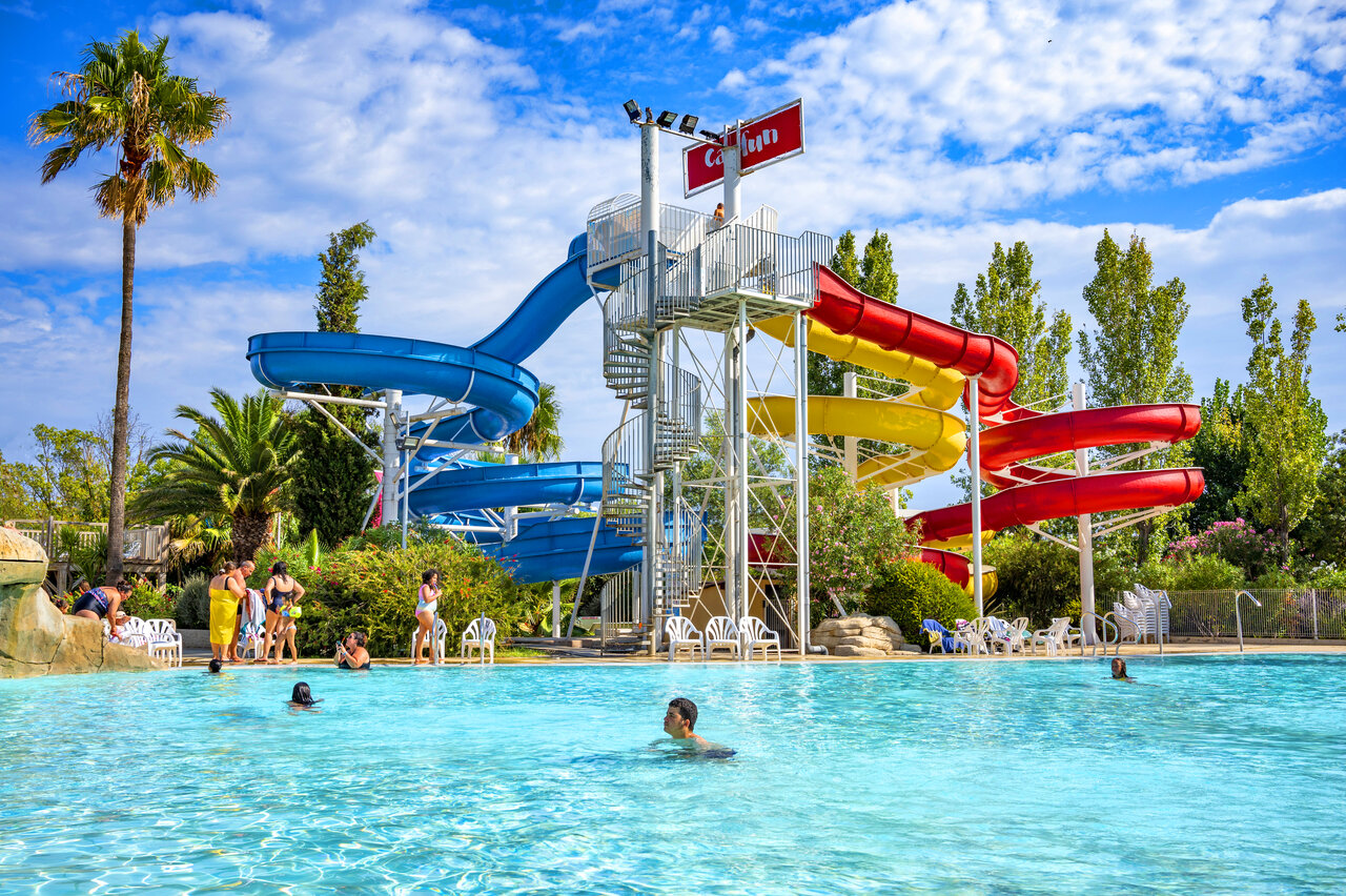 Piscina exterior con toboganes coloridos en el camping CAPFUN Fleurs d'Agde en AGDE (34).