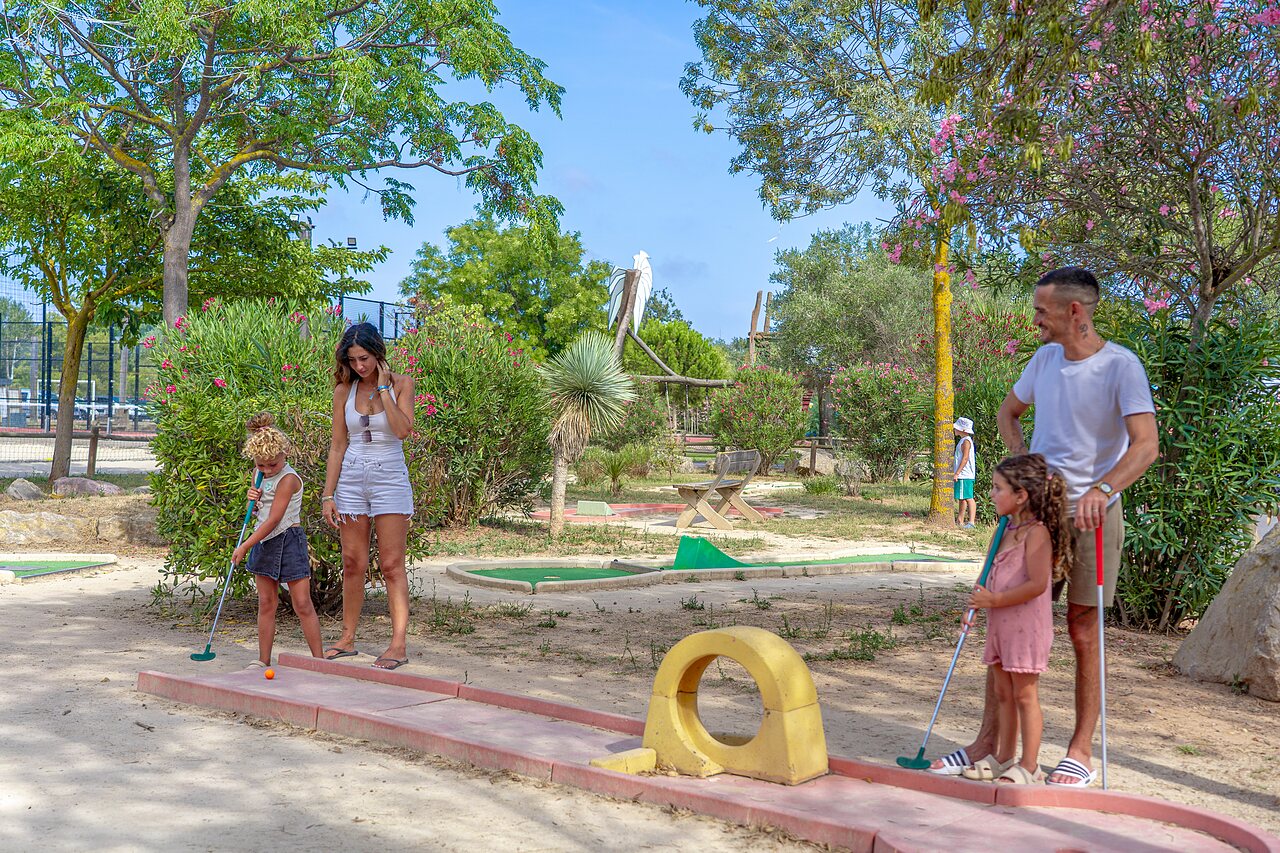 Familia jugando al minigolf en un campo exterior en el camping CAPFUN Fleurs d'Agde en AGDE (34).
