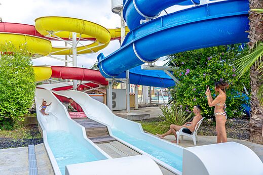 Toboganes acuáticos coloridos y niño deslizándose en el camping CAPFUN Fleurs d'Agde en AGDE (34).
