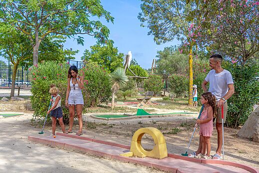 Familia jugando al minigolf en un campo exterior en el camping CAPFUN Fleurs d'Agde en AGDE (34).