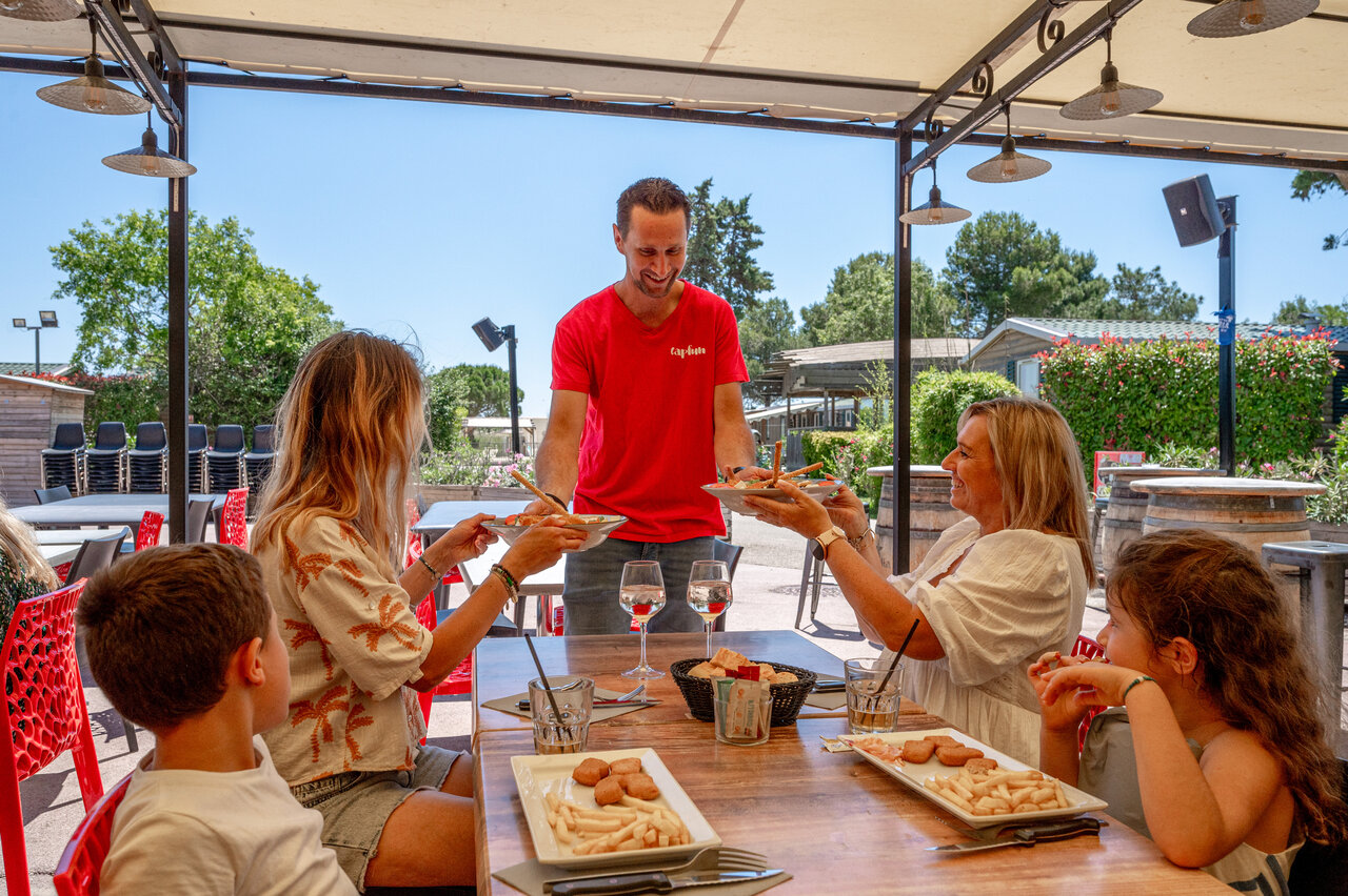 Familia almorzando en restaurante Capfun en el camping CAPFUN Fleur de Camargue en Saint-Laurent-d Aigouze.