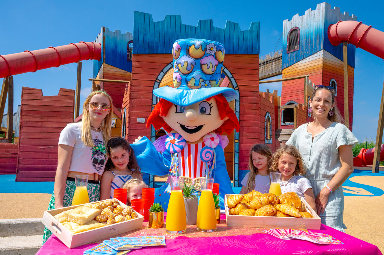 Mascota y ni�os disfrutando de un desayuno festivo frente al parque infantil en el camping CAPFUN Fleur de Camargue en Saint-Laurent-d Aigouze (30).