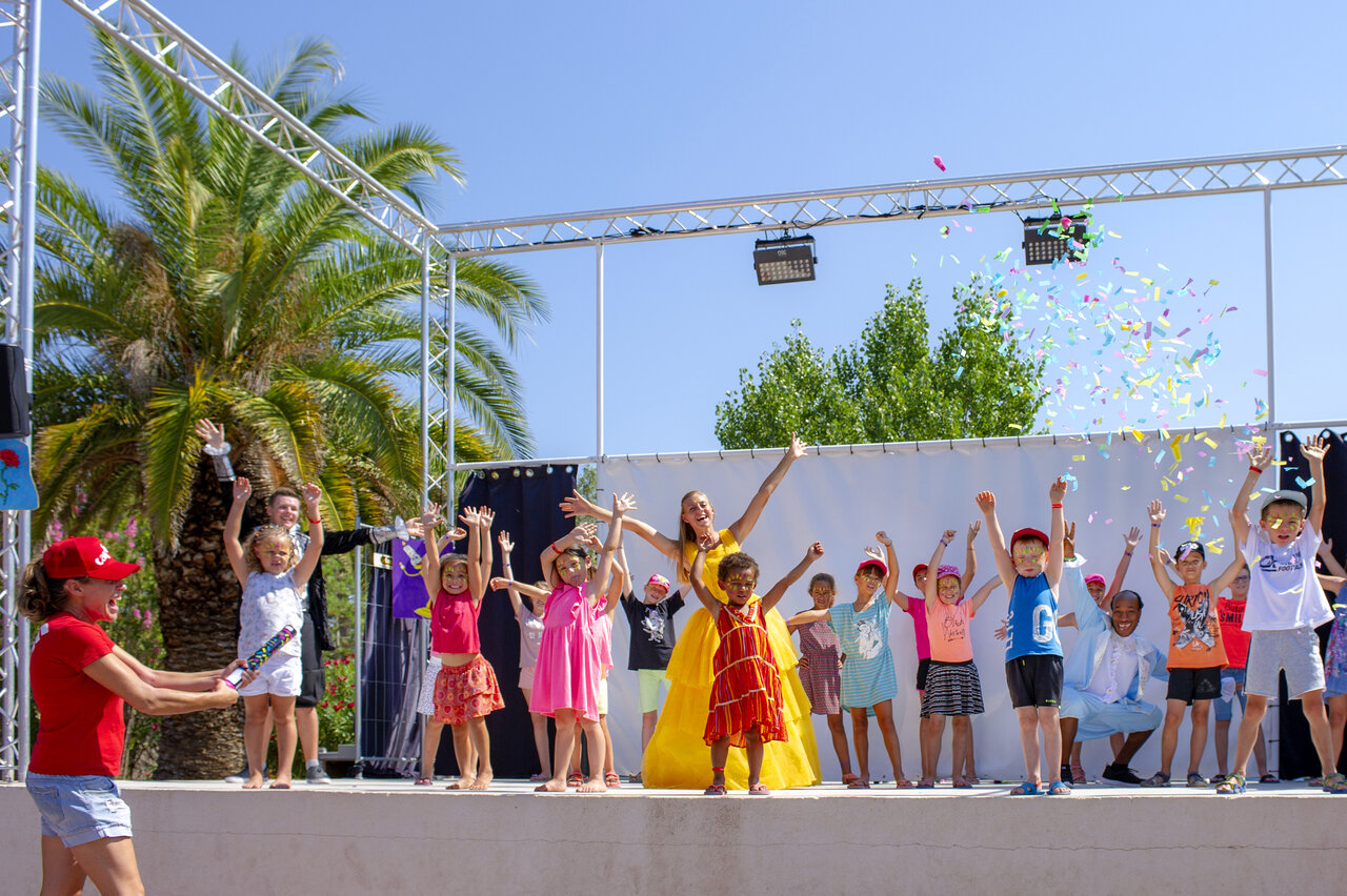 Ni�os y animadores felices en el escenario con confeti en el camping CAPFUN Fleur de Camargue en Saint-Laurent-d Aigouze (30).