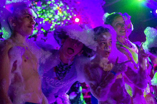 Fiesta de la espuma animada con jóvenes y luces de colores en el camping CAPFUN Fleur de Camargue en Saint-Laurent-d Aigouze (30).