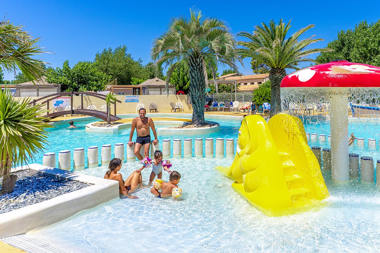 Piscina exterior, tobog�n amarillo y juegos en el camping CAPFUN Flots Bleus en VIAS PLAGE (34).