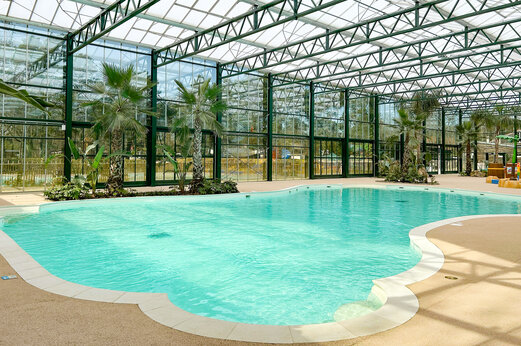 Piscina cubierta climatizada con palmeras en el camping CLICOCHIC La Forêt d'Azalée.