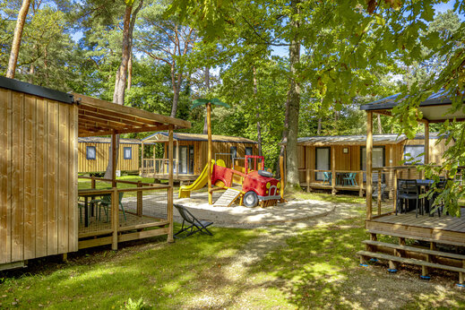 Mobil-homes de madera y zona de juegos en camping CLICOCHIC La Forêt d'Azalée.
