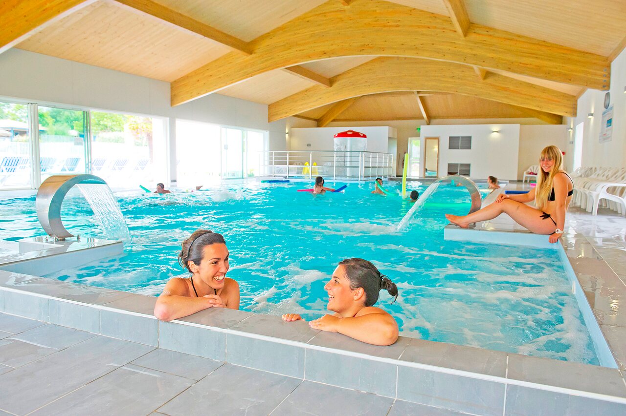 Piscina cubierta climatizada con chorros de agua y ba�istas en el camping CAPFUN Forges en Avrille (85).