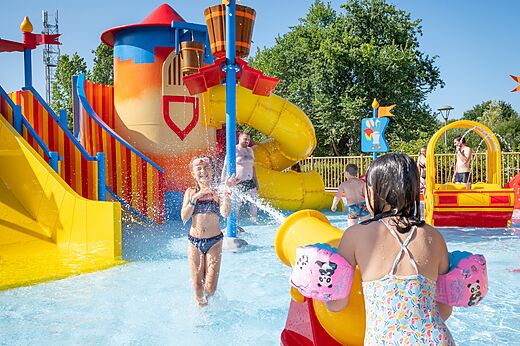 Zona de juegos acu�ticos con toboganes y ni�os felices en el camping CAPFUN Forges en Avrille (85).