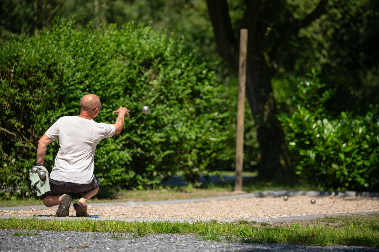 Hombre jugando a la petanca en una cancha de petanca en el camping CAPFUN Fort Bedmar en Sint-Gillis-Waas.