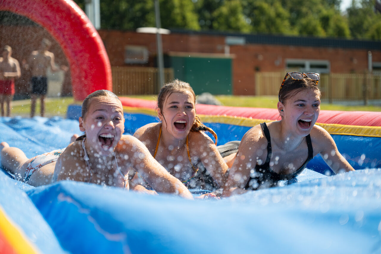 Chicas riendo en tobog�n acu�tico inflable en el camping CAPFUN Fort Bedmar en Sint-Gillis-Waas.