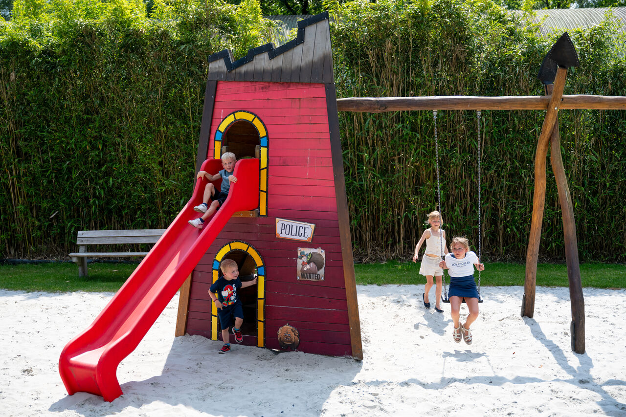 Zona de juegos con tobog�n y columpios para ni�os en el camping CAPFUN Fort Bedmar en Sint-Gillis-Waas.