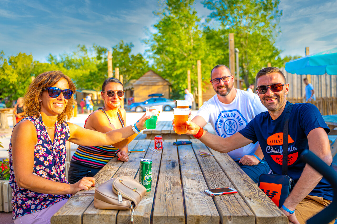 Amigos brindando en el bar exterior del camping CAPFUN Fort Falabraque en Seltz (67).