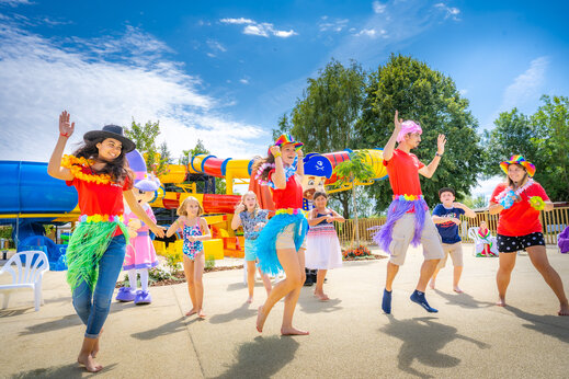Animación festiva, bailarines y niños cerca de toboganes en camping CAPFUN Fort Falabraque en Seltz.